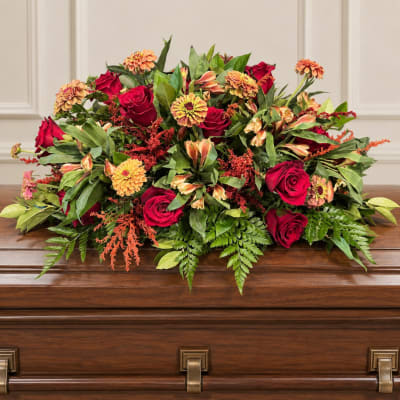 Red roses and orange flowers arranged on a casket