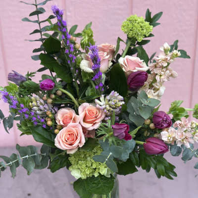 Mixed bouquet with pink roses, purple tulips, and green accents