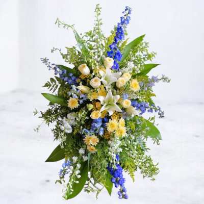 Tall floral spray with white lilies, cream roses, and blue flowers