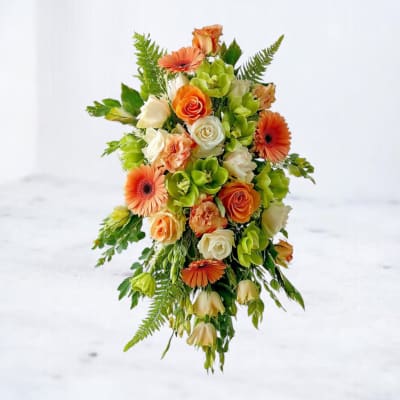 Cascading arrangement of orange, white, and green flowers with trailing greenery