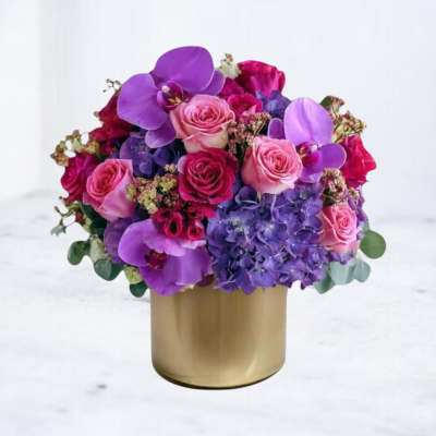 Pink and purple flower arrangement in a gold vase