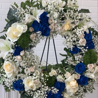 Heart-shaped floral wreath with blue and cream roses on a stand