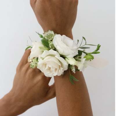 White floral wrist corsage on a person's wrist
