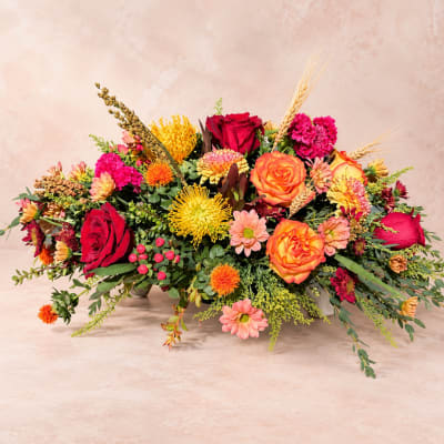 Low floral arrangement with red and orange roses and mixed blooms