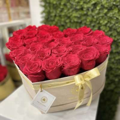 Heart-shaped beige box filled with red roses and tied with a yellow ribbon