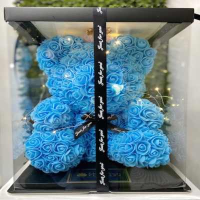Blue rose teddy bear in a clear display box with black ribbon