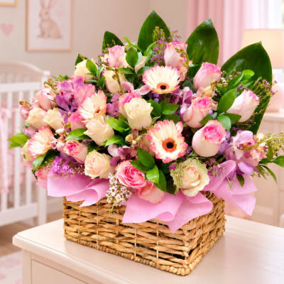 Pink and cream flower arrangement in a wicker basket