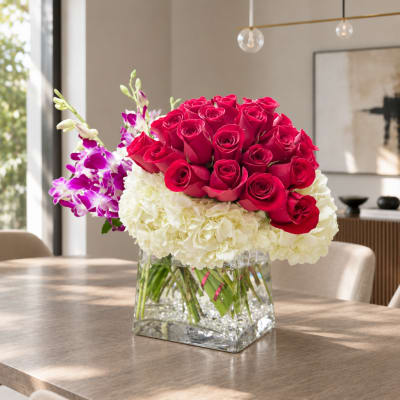 Bouquet of red roses, white hydrangeas, and purple orchids in a glass vase