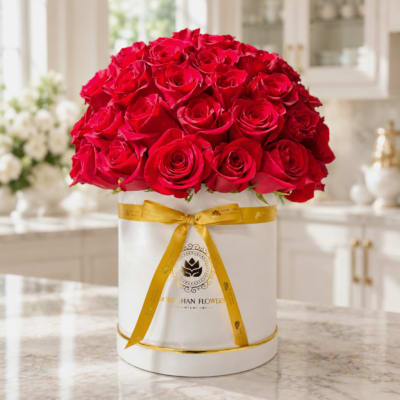 Red roses arranged in a white round box with a gold ribbon