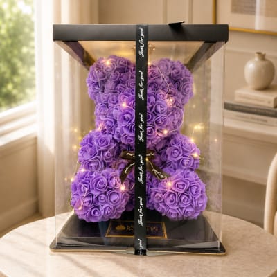 Purple rose teddy bear in a clear gift box with a ribbon