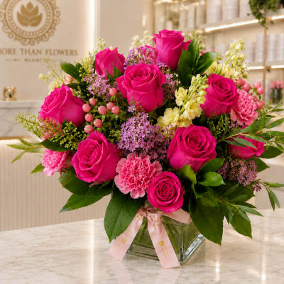 Hot pink roses and pink carnations in a clear glass vase with a ribbon