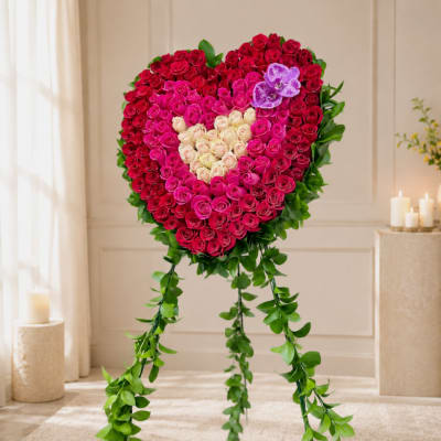 Heart-shaped rose arrangement on a stand with hanging greenery