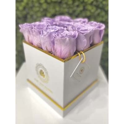 Lavender roses arranged in a white square hat box with gold trim