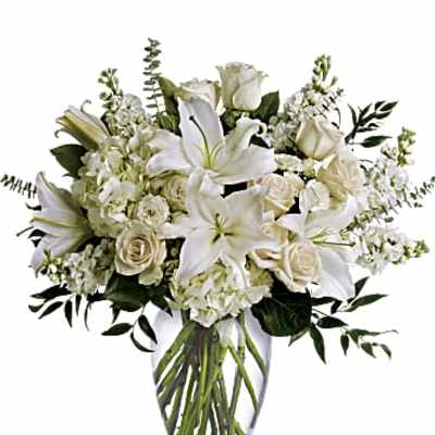 White lilies and roses arranged in a clear glass vase