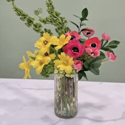 Bright yellow and pink flowers in a clear glass vase