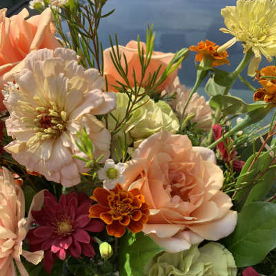 Mixed bouquet with peach roses, yellow and burgundy blooms in a warm, sunlit arrangement