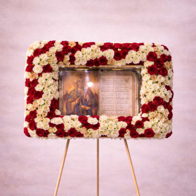 Tall standing rectangular wreath of red and white roses framing a religious icon on an easel.