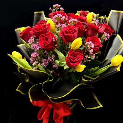 Bouquet of red roses and yellow tulips wrapped in black paper