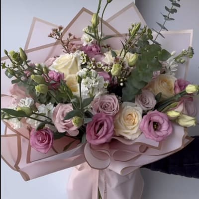 Pink and white bouquet of roses and lisianthus wrapped in blush paper