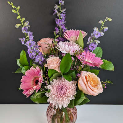 Pink and lavender flowers arranged in a glass vase