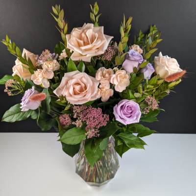 Bouquet of blush and lavender roses in a clear glass vase