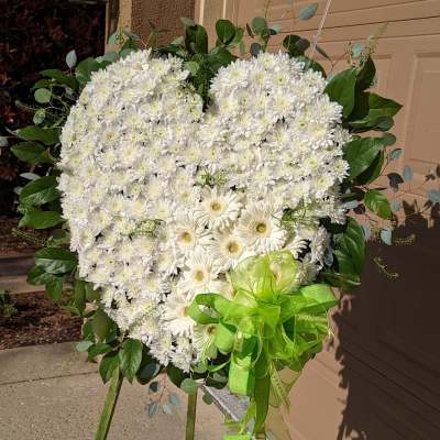 Heart-shaped white floral standing spray with a green ribbon bow