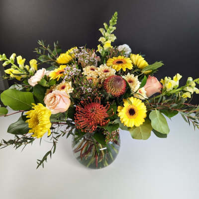 Mixed yellow and peach flowers in a glass vase