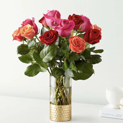 Bouquet of pink, red, and orange roses in a clear glass vase