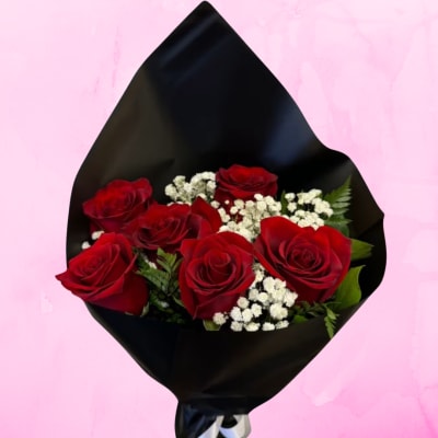 Bouquet of red roses and white filler flowers wrapped in black paper