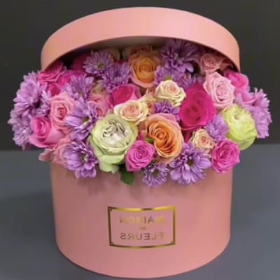 Pink hatbox filled with roses and purple daisies