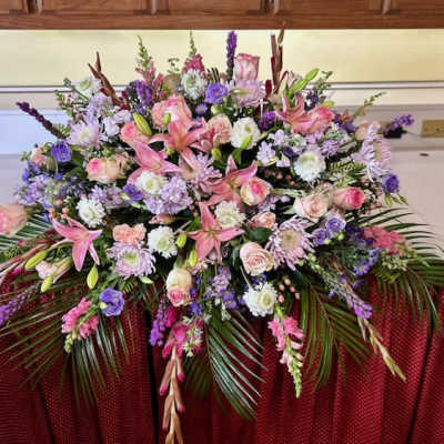 Large floral spray with pink lilies, roses, and purple blooms