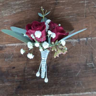 Small boutonniere with burgundy roses, white baby's breath, and silver ribbon