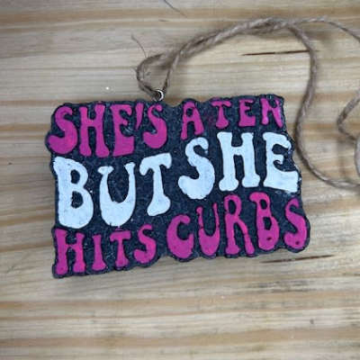 Handmade hanging sign with pink and white text on a black background