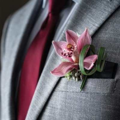 Pink orchid boutonniere pinned to a gray suit jacket