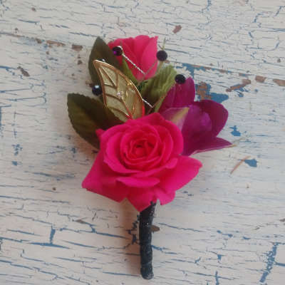 Pink rose boutonniere with decorative leaves and beads