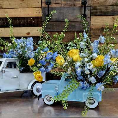 Two toy pickup trucks filled with blue and yellow flowers