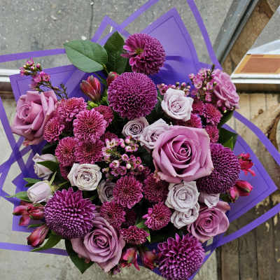 Bouquet of purple roses and magenta chrysanthemums wrapped in purple paper