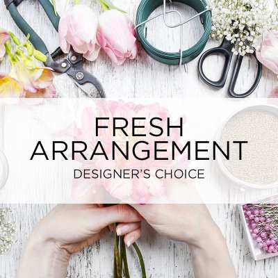 Hands holding pink tulips beside floral arranging tools and supplies