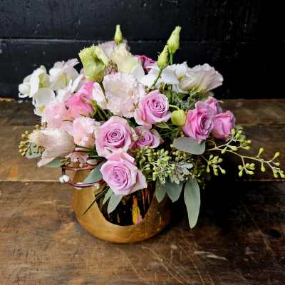 Pink roses and white blooms arranged in a gold vase