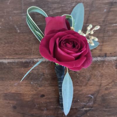 Single deep pink rose boutonniere with blue-green leaves