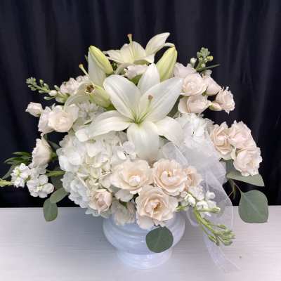 White lilies and pale blush roses in a white vase