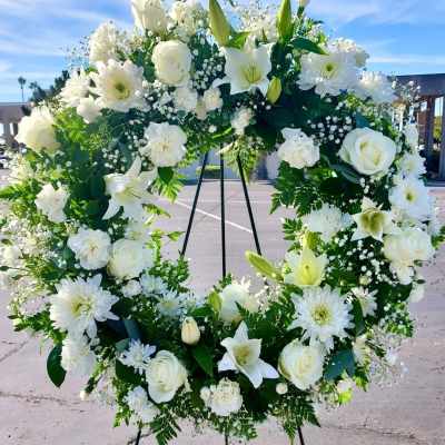 White floral wreath on a black stand outdoors