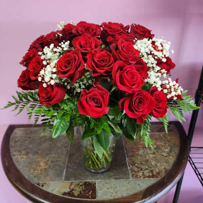 Red roses and white baby's breath arranged in a clear glass vase