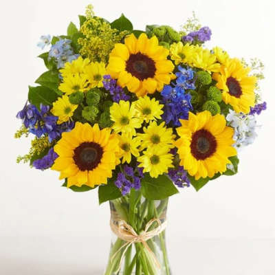Bouquet of yellow sunflowers and mixed blue-purple flowers in a glass vase