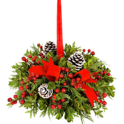 Red taper candle in a holiday greenery arrangement with pinecones and berries