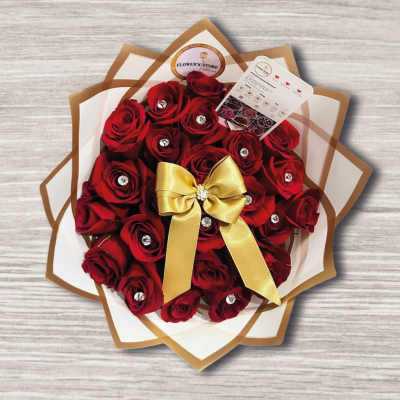 Bouquet of red roses wrapped in white and brown paper with a gold bow