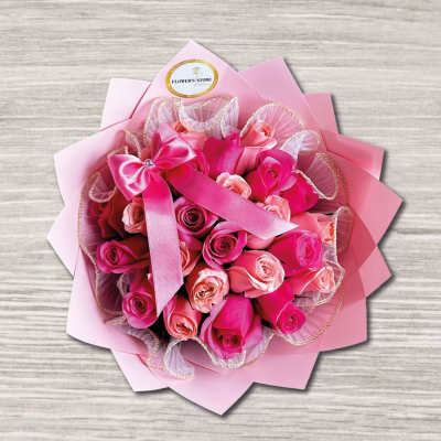 Pink rose bouquet wrapped in layered pink paper with a ribbon bow