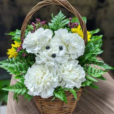 White carnations arranged in a wicker basket with yellow and purple accents