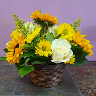 Yellow flowers and a white rose in a woven basket