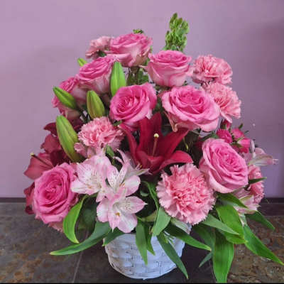 Pink roses and lilies arranged in a white basket